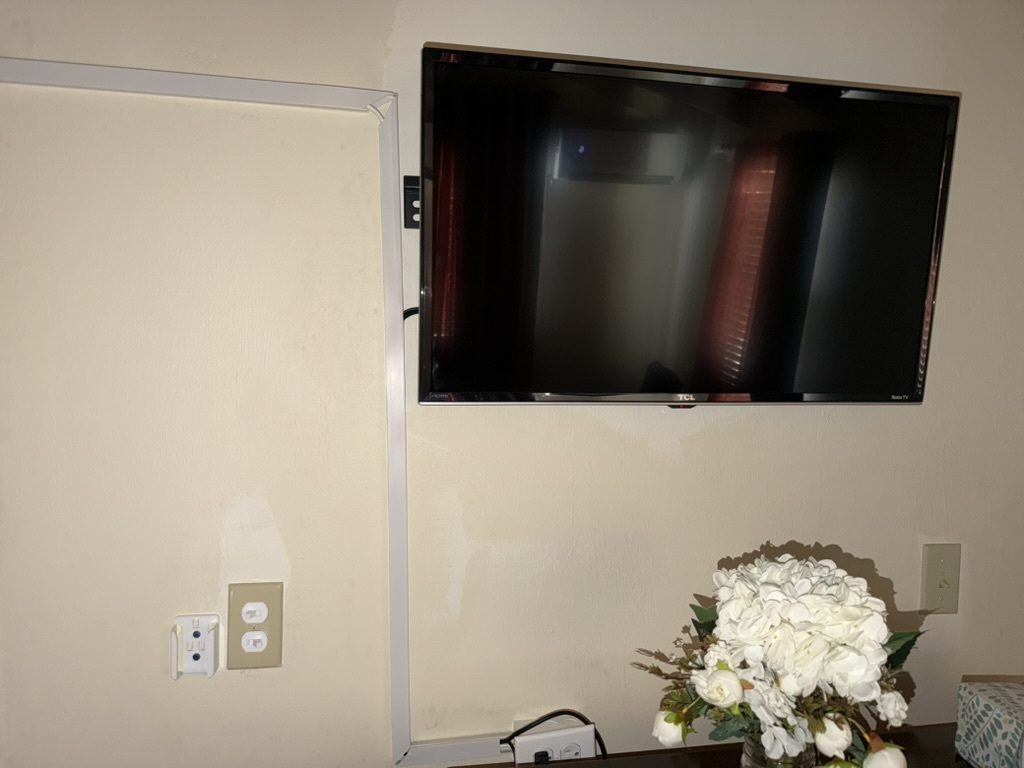 TV wall mount installation in Airbnb bedroom — clean cable management