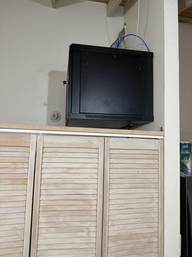 Wall-mount network rack enclosure installed above cabinet