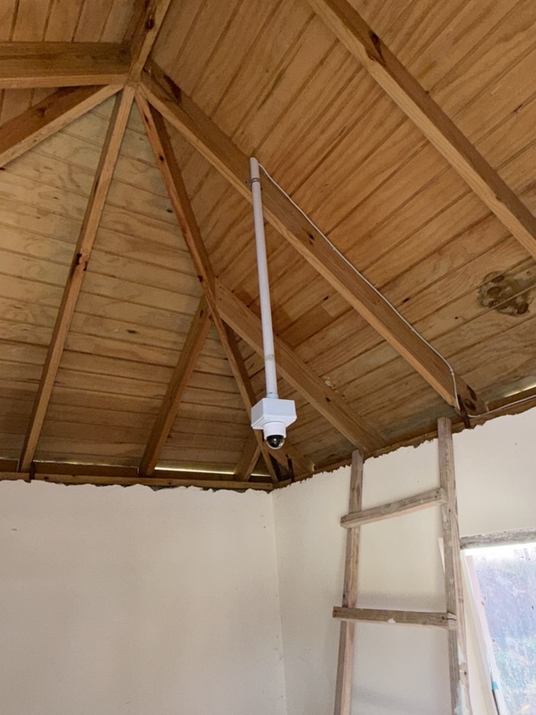 UniFi dome camera mounted on ceiling rafter with conduit run — indoor security install