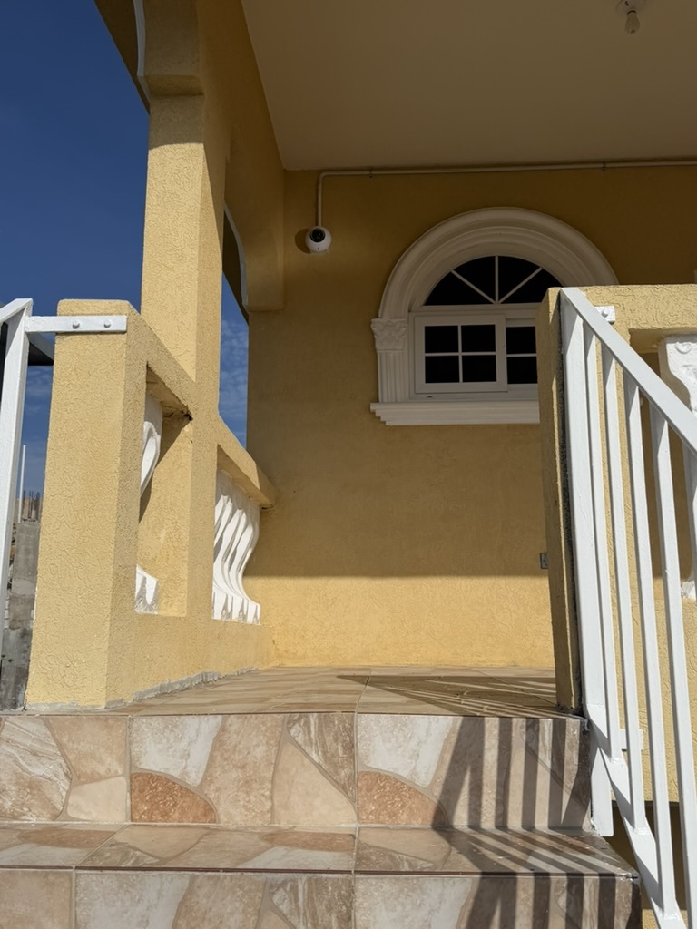 UniFi dome camera mounted on exterior wall above staircase entrance